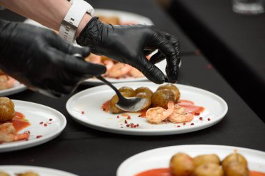 Siyah masa arkasında servis edilen geleneksel İspanyol tapaları. Gambas Ajillo ile Patatas Bravas.