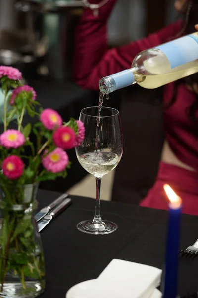 white wine is poured into a glass by the sommelier