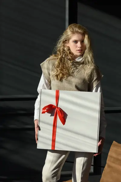 Eine Frau Hält Eine Weiße Geschenkschachtel Mit Roter Schleife Der lizenzfreie Stockbilder