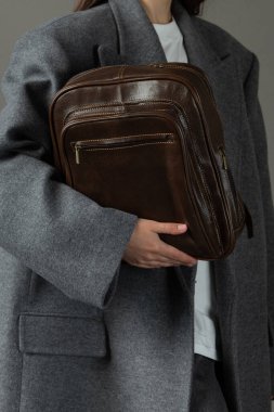 Deri sırt çantalı, gri ceketli bir kadın. .