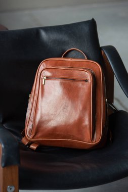 Brown leather backpack on the stylish chair.