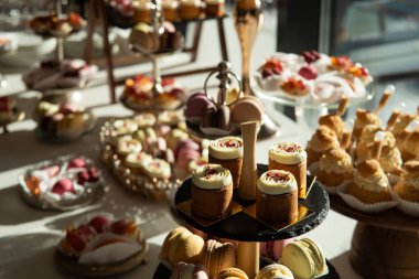 Çeşitli tatlı ve hamur işleriyle dolu bir masa. Tatlılar cam kaseler ve tepsilerde sıralanır..