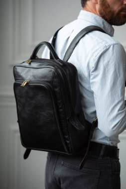 Şık bir adam çantasıyla çağdaş bir odada duruyor, şehir tarzı ve profesyonelliği somutlaştırıyor..