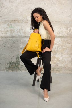 Moda modasına uygun bir model, canlı sarı bir sırt çantası ile modern bir kıyafet sergiliyor.