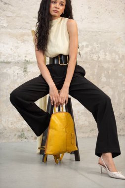 Moda modasına uygun bir model, canlı sarı bir sırt çantası ile modern bir kıyafet sergiliyor.