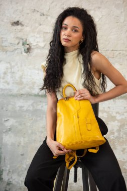 Moda modasına uygun bir model, canlı sarı bir sırt çantası ile modern bir kıyafet sergiliyor.