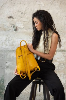 Moda modasına uygun bir model, canlı sarı bir sırt çantası ile modern bir kıyafet sergiliyor.
