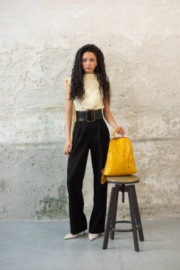 Moda modasına uygun bir model, canlı sarı bir sırt çantası ile modern bir kıyafet sergiliyor.