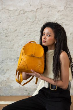 Moda modasına uygun bir model, canlı sarı bir sırt çantası ile modern bir kıyafet sergiliyor.