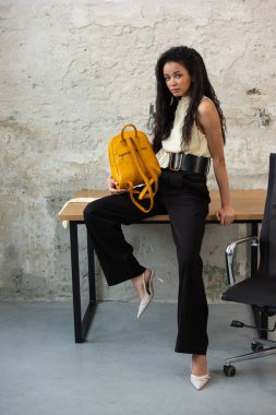 Moda modasına uygun bir model, canlı sarı bir sırt çantası ile modern bir kıyafet sergiliyor.