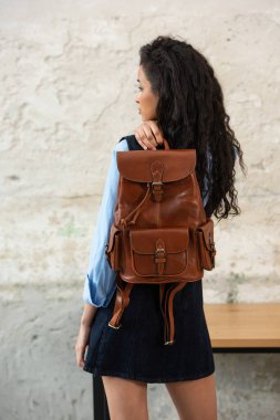 Moda modasına uygun bir model, kahverengi bir sırt çantası ile modern bir kıyafet sergiliyor.