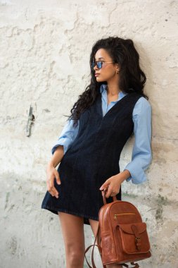 Moda modasına uygun bir model, kahverengi bir sırt çantası ile modern bir kıyafet sergiliyor.