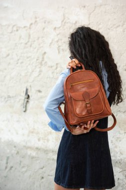 Moda modasına uygun bir model, kahverengi bir sırt çantası ile modern bir kıyafet sergiliyor.