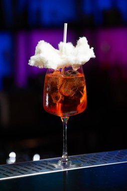 Arka planda koyu mavi ve mor renkli bulanık bir karışım var. Bu da modern bir bar ya da dinlenme odası atmosferi olduğunu gösteriyor.