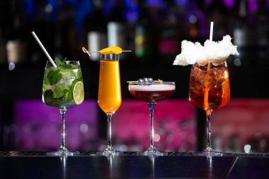 Bulanık arka plan, çeşitli ışık ve şişelerle dolu canlı bir gece hayatı ortamı olduğunu gösteriyor. Seçici odak