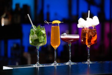 Bulanık arka plan, çeşitli ışık ve şişelerle dolu canlı bir gece hayatı ortamı olduğunu gösteriyor. Seçici odak