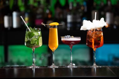 Bulanık arka plan, çeşitli ışık ve şişelerle dolu canlı bir gece hayatı ortamı olduğunu gösteriyor. Seçici odak