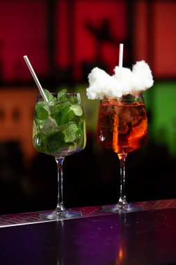 Kırmızı, yeşil ve siyahın bulanık arkaplanı canlı bir bar ya da kulüp ortamını işaret ediyor..