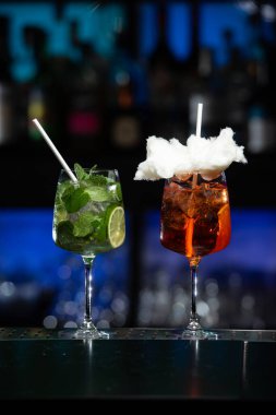 Kırmızı, yeşil ve siyahın bulanık arkaplanı canlı bir bar ya da kulüp ortamını işaret ediyor..