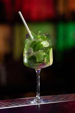 Bulanık arka plan kırmızı, mavi ve mor ışıkların karışımını içeriyor. Bu da canlı bir bar atmosferini işaret ediyor.