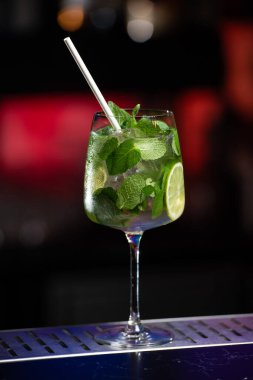 Bulanık arka plan kırmızı, mavi ve mor ışıkların karışımını içeriyor. Bu da canlı bir bar atmosferini işaret ediyor.