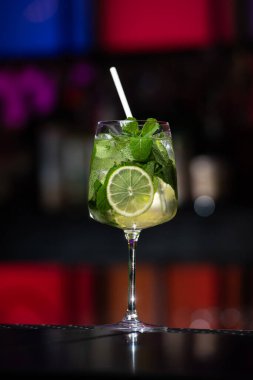 Bulanık arka plan kırmızı, mavi ve mor ışıkların karışımını içeriyor. Bu da canlı bir bar atmosferini işaret ediyor.