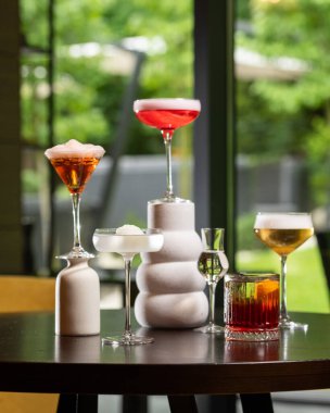 Renk ve sunum olarak değişen beş farklı alkollü kokteyl koleksiyonu bulanık bir arka plana karşı sanatsal bir şekilde karanlık bir masada düzenlenmiştir. .