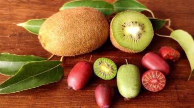Aktinidia arguta Kens Kırmızı ve yeşil Rogow mini kivi büyük kivi meyveleri karşılaştırmak için küçük ahşap arka plan full-HD