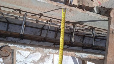 Olgun inşaat işçisi formaliteleri mezurayla ölçüyor.