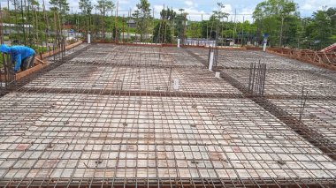 İnşaat işçisi inşaat alanındaki beton zemine beton döküyor.