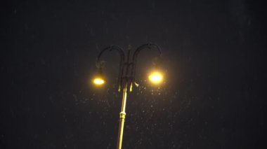 Geceleri gerçek kar yağışı ve çerçevenin ortasında sokak lambası. Yüksek kalite 4k görüntü