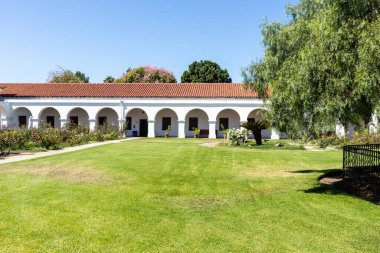 OCEANSIDE, CALIFORNIA, ABD - 3 Eylül 2021: The Mission San Luis Rey avlusu, 1830 'da dikilmiş bir biber ağacı ile birlikte ve California' da türünün ilk örneği olarak bilinen.