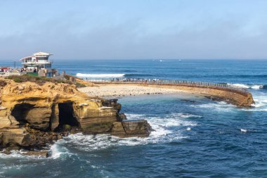 LA JOLLA, CALIFORNIA - 10 Mayıs 2025: cankurtaran istasyonu ve tarihi La Jolla Çocuk Havuzu. Deniz kıyısı 1931 'de çocuklar için bir oyun alanı olarak inşa edildi ve onları dalgalardan korumak için..  