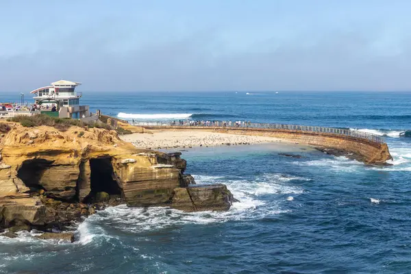 LA JOLLA, CALIFORNIA - 10 Mayıs 2025: cankurtaran istasyonu ve tarihi La Jolla Çocuk Havuzu. Deniz kıyısı 1931 'de çocuklar için bir oyun alanı olarak inşa edildi ve onları dalgalardan korumak için..  