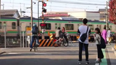 Tokyo, Japonya 3 Kasım 2023: Bekleyen yaya ve bisikletçilerle Demiryolu Kavşağında Tren Geçidi