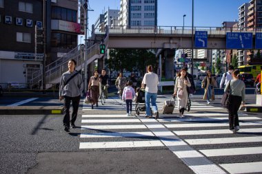 Tokyo, Japonya, 26 Ekim 2023: Meşgul bir kavşakta karşıdan karşıya geçen yayalar