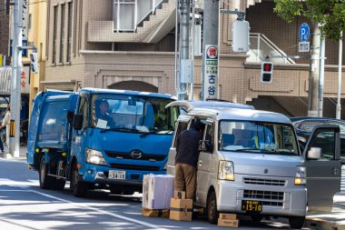 Tokyo, Japonya, 26 Ekim 2023: Yoğun Cadde 'de kargo araçları ve işçiler paketleri boşaltıyor