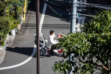 Tokyo, Japonya, 26 Ekim 2023: Tokyo 'da yaya geçidinde scooter süren bir kadın.