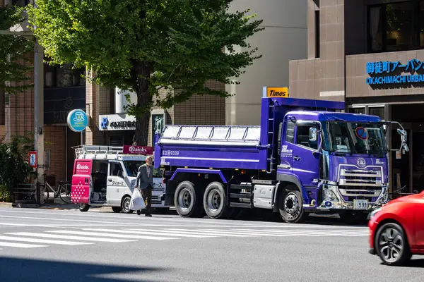 Tokyo, Japonya, 26 Ekim 2023: Ticari binalarla şehir yolunda hareket halindeki inşaat kamyonu.