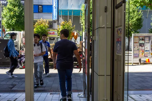 Tokyo, Japonya, 26 Ekim 2023: İnsanlar bir alışveriş salonunun girişinden geçiyor