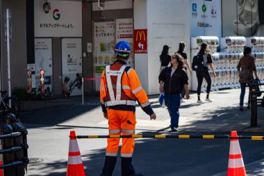 Tokyo, Japonya, 26 Ekim 2023 Tokyo 'da trafik akışını yöneten inşaat işçisi.