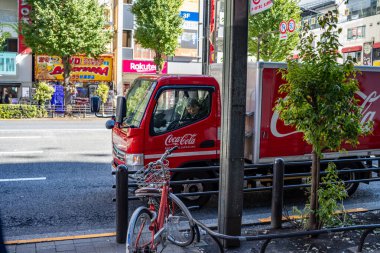 Tokyo, Japonya, 26 Ekim 2023: Coca-Cola teslimat kamyonu kaldırıma park edilmiş, önünde bir bisikletle