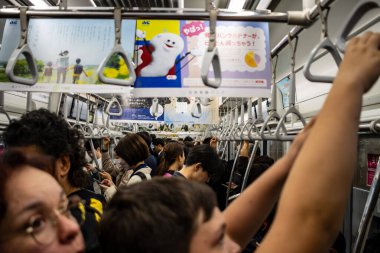 Tokyo, Japonya, 26 Ekim 2023: Kalabalık bir Tokyo metrosunun içinde reklam ile birlikte