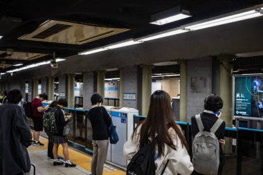 Tokyo, Japonya, 26 Ekim 2023: Bir metro istasyonunda trene binmeyi bekleyen yolcular