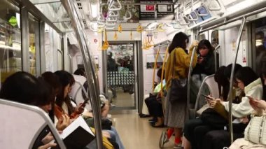 Tokyo, Japonya, 22 Kasım 2023: Bir Tokyo trenindeki banliyö sakinleri ulaşım sırasında telefonlarına kaydedildi