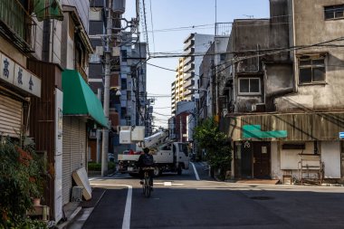 Tokyo, Japonya, 27 Kasım 2023: Bisikletçi ve Geleneksel Mimariyle Sessiz Konut Caddesi