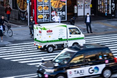 Tokyo, Japonya, 27 Ekim 2023: Reklam panolarının yakınındaki şehir trafiğinde markalı dağıtım kamyonu