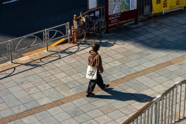 Tokyo, Japonya, 27 Ekim 2023: Şehirde kapalı bir dükkanın önünden geçen yayalar