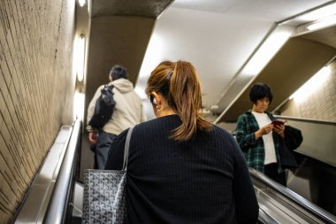 Tokyo, Japonya, 27 Ekim 2023: Tokyo metro istasyonunda yürüyen merdiven yolcuları