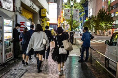 Tokyo, Japonya, 27 Ekim 2023: Bir grup insan gece kaldırımda yürüyor